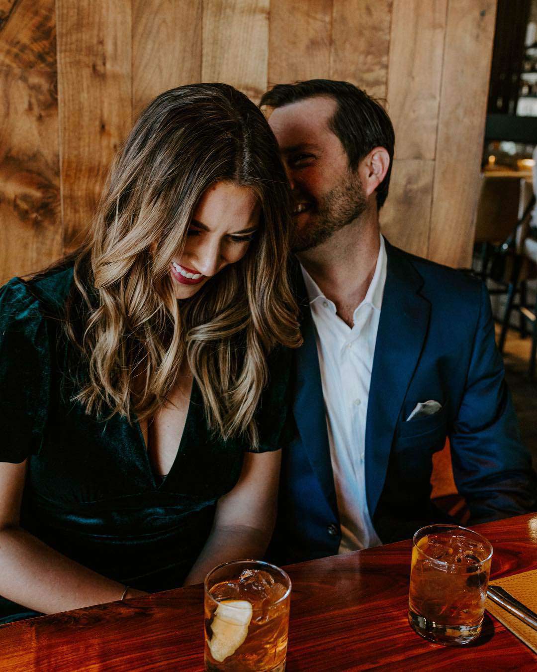 a man whispering into the ear of a smiling woman