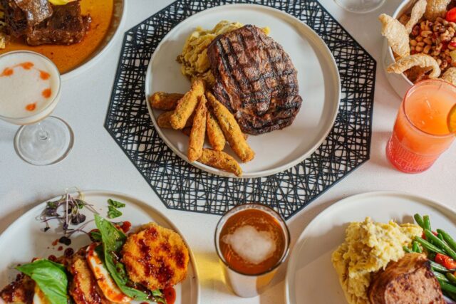 Grilled steak with fries, sides, and drinks on a dining table