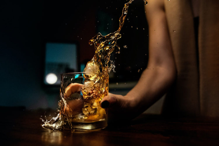woman slamming cocktail glass down on counter with artistic spill