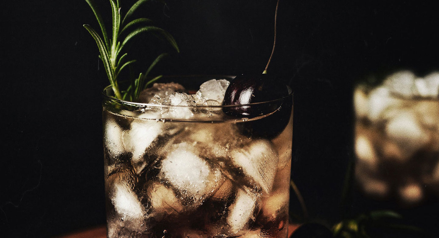 close up of cocktail with garnish in dim lighting