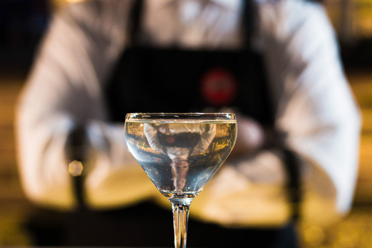 bartender standing behind poured cocktail drink