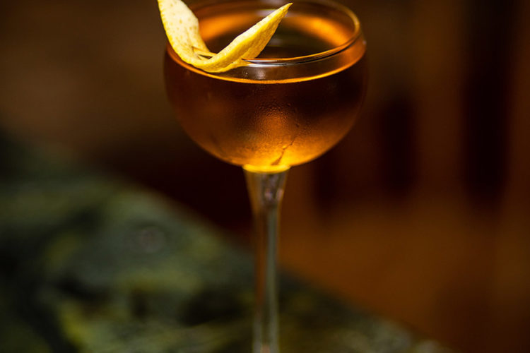 cocktail in long stemmed glass with orange peel garnish