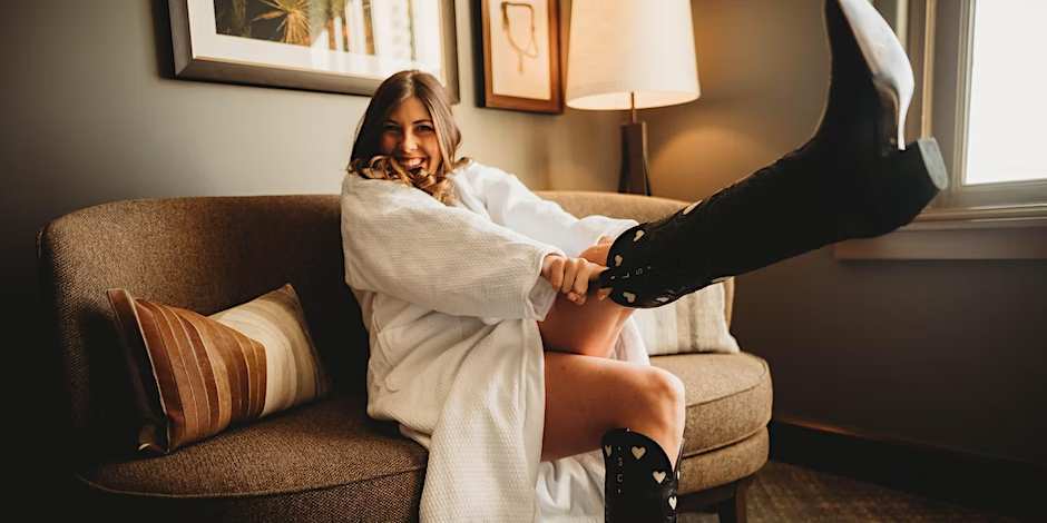 woman in a dressing gown pulling on cowboy boots