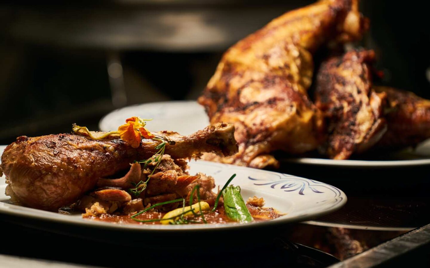 Thanksgiving turkey in background with a piece on a plate in the foreground