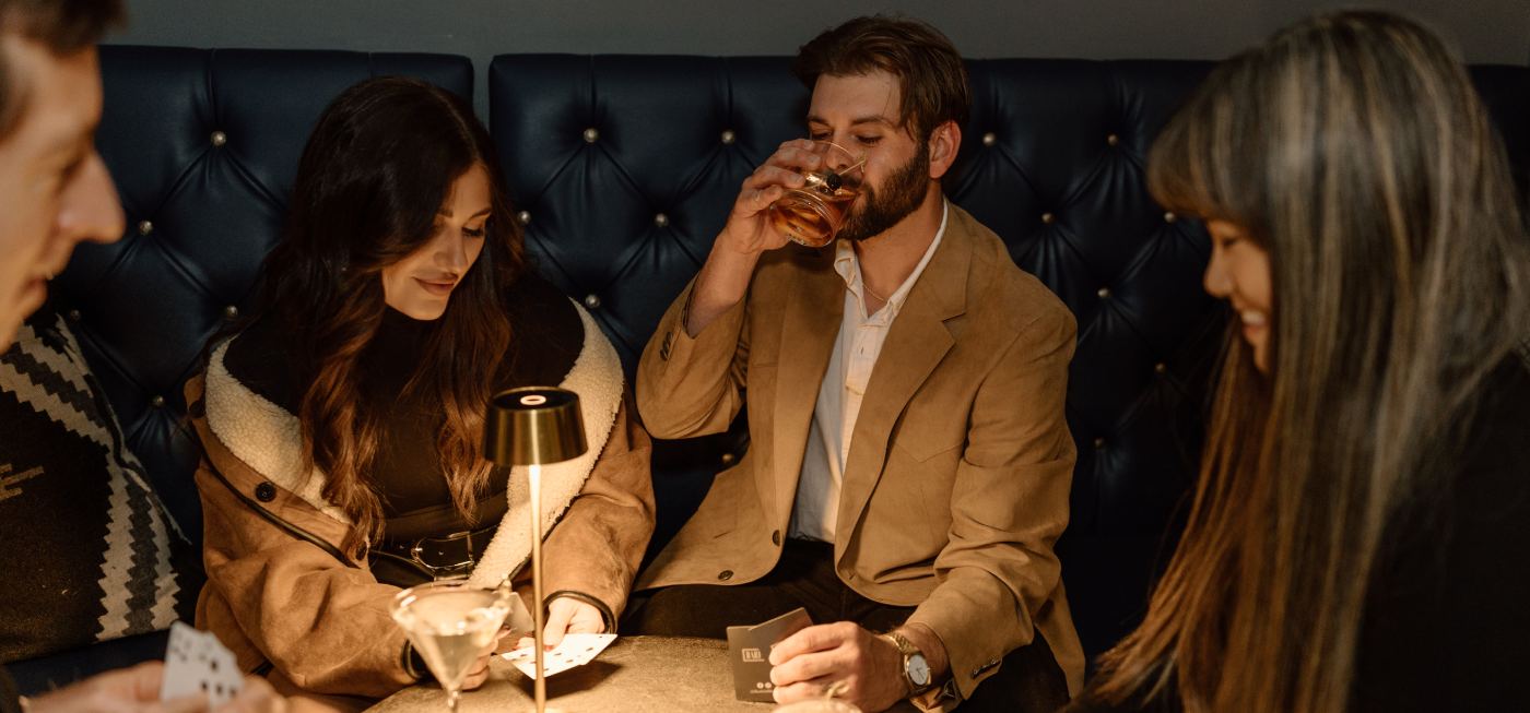 Group enjoying drinks and playing cards in a lounge setting.