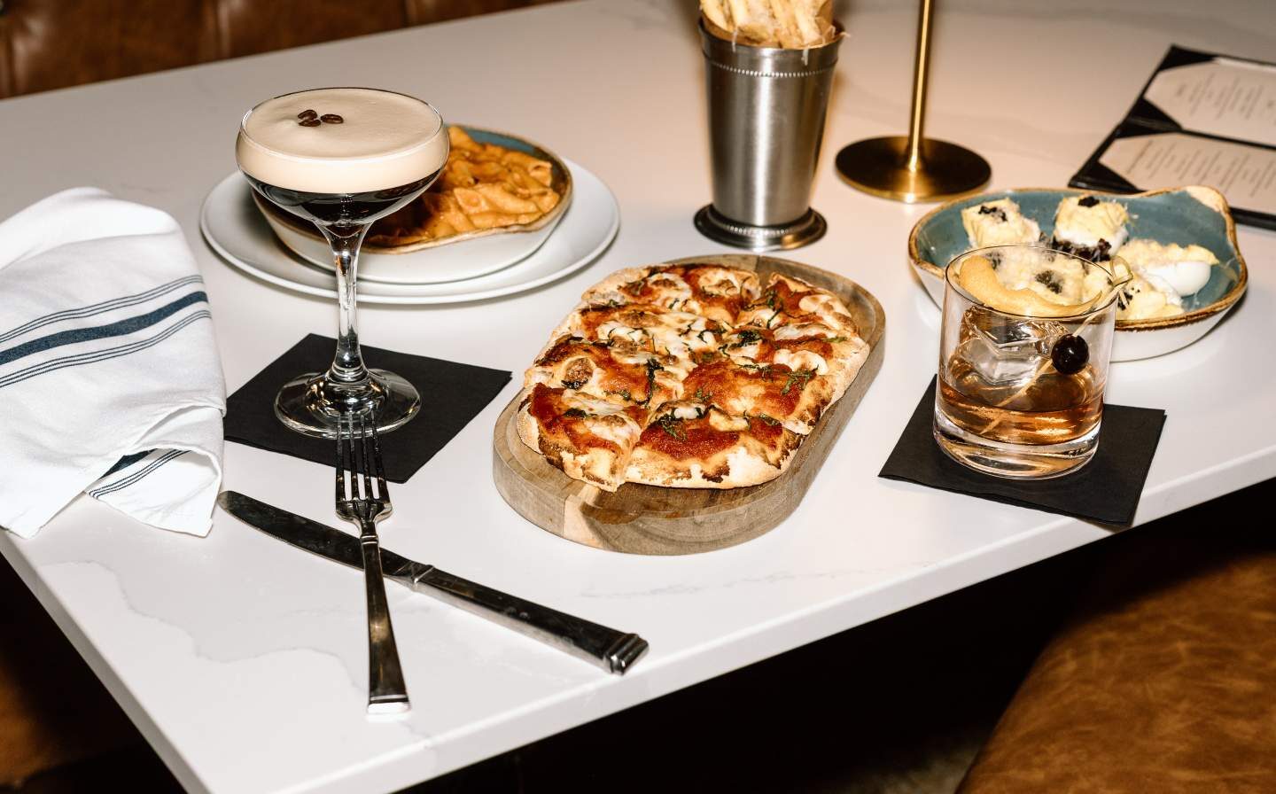 Pizza, pasta, and appetizers served with cocktails on a table.