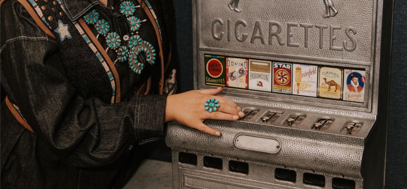Person selecting a cigarette from a vintage vending machine.
