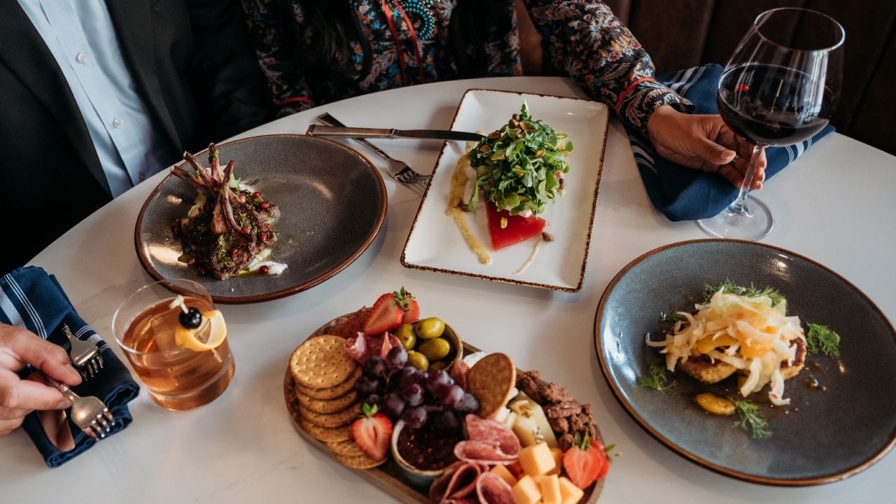 Couple enjoying a variety of dishes and wine at a restaurant table.