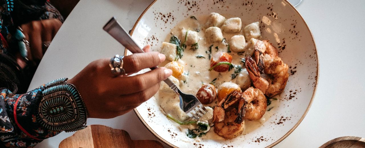 Creamy gnocchi with shrimp being served at a restaurant.