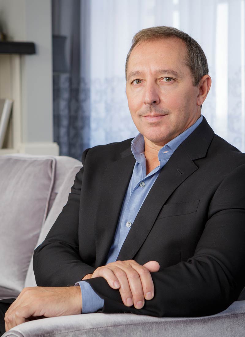 paul coury smiling on a plush couch