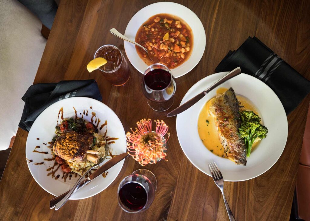 Three dishes and drinks are spread out on a table at Flint in Oklahoma City