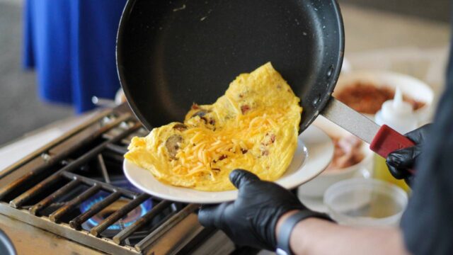 Chef plating a fresh custom omelet at a breakfast buffet station.