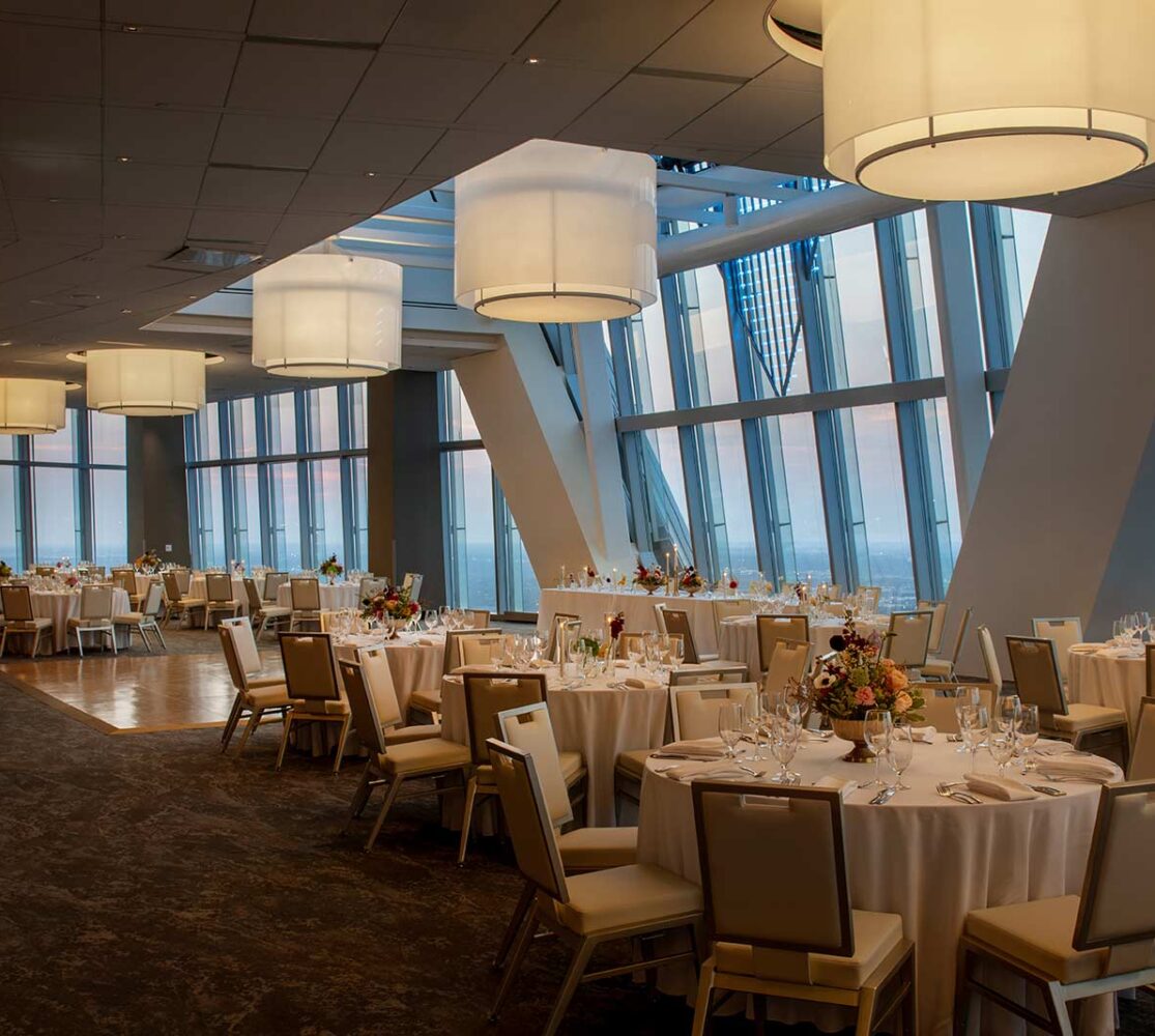 meeting space with many set tables surrounded by chairs lit by large circular lighting fixtures