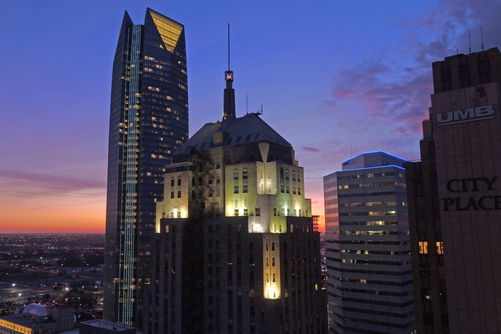Downtown Oklahoma City skyline at sunset with illuminated skyscrapers and office buildings.
